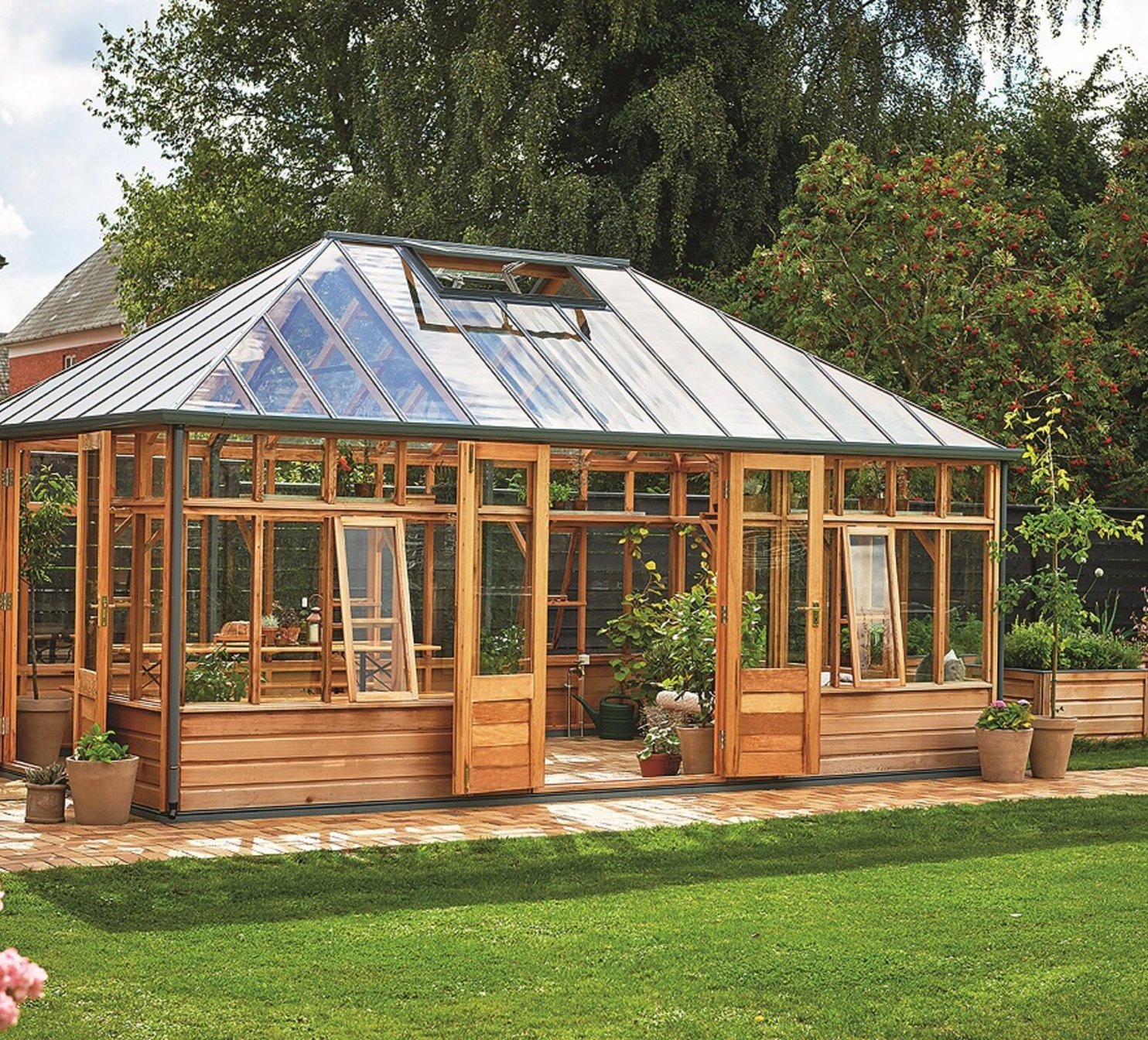 Dřevěný viktorianský skleník na zahradě s květinami