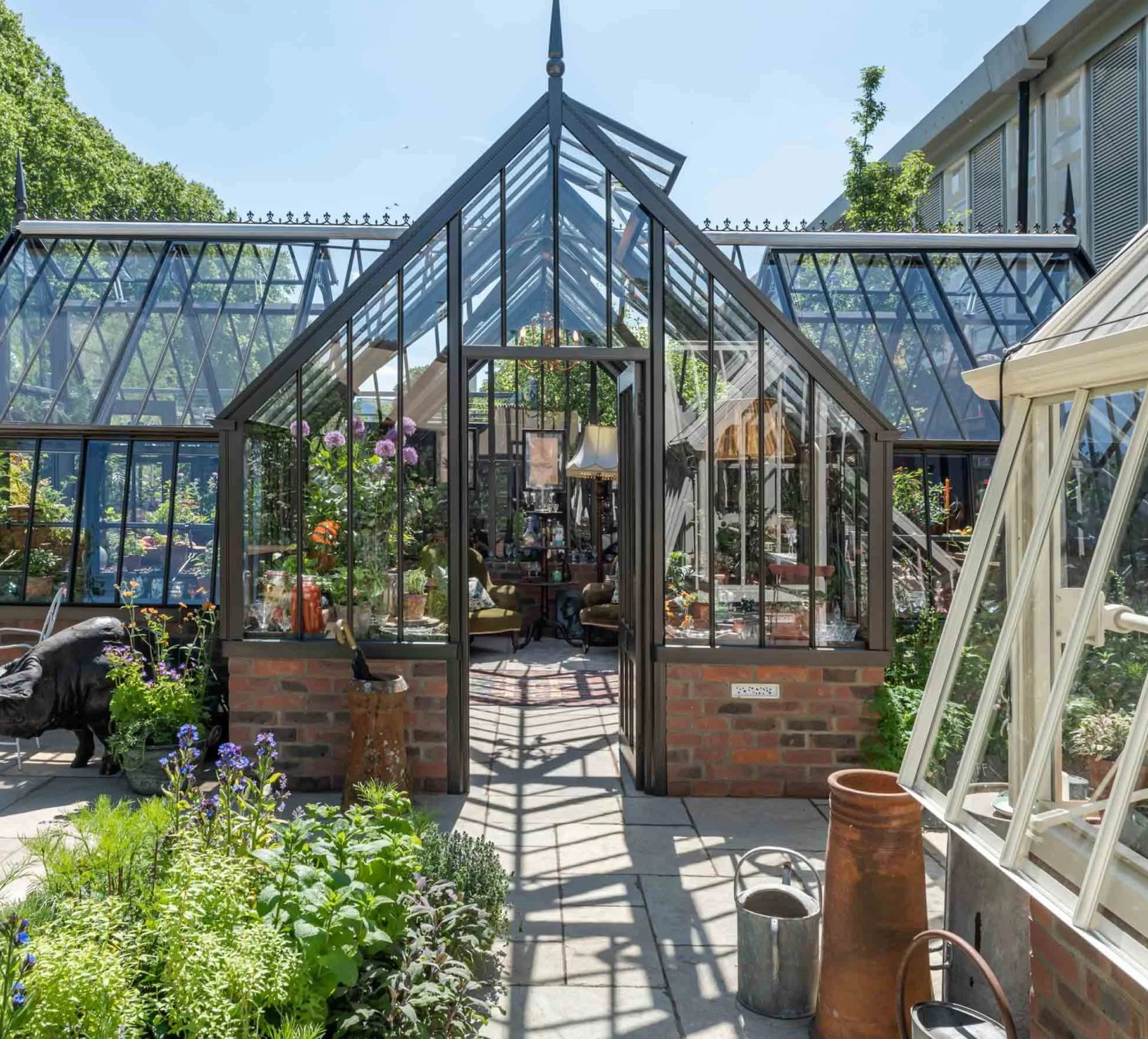 Hliníkový viktorianský skleník na zahradě s květinami