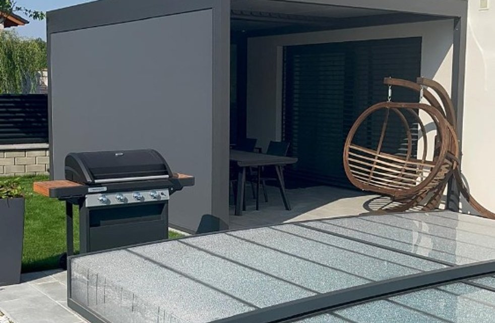 Moderní hliníková pergola u rodinného domu s bioklimatickou střechou, krytým posezením a zakrytým bazénem – prémiové venkovní stínění Hezký stín.