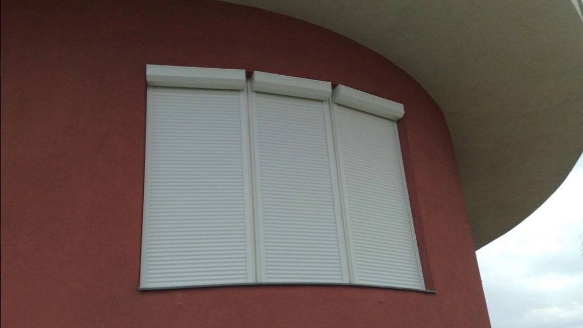 Předokenní rolety na obloukovém okně – tři segmenty s bílými boxy, čisté řešení i pro zaoblenou fasádu.