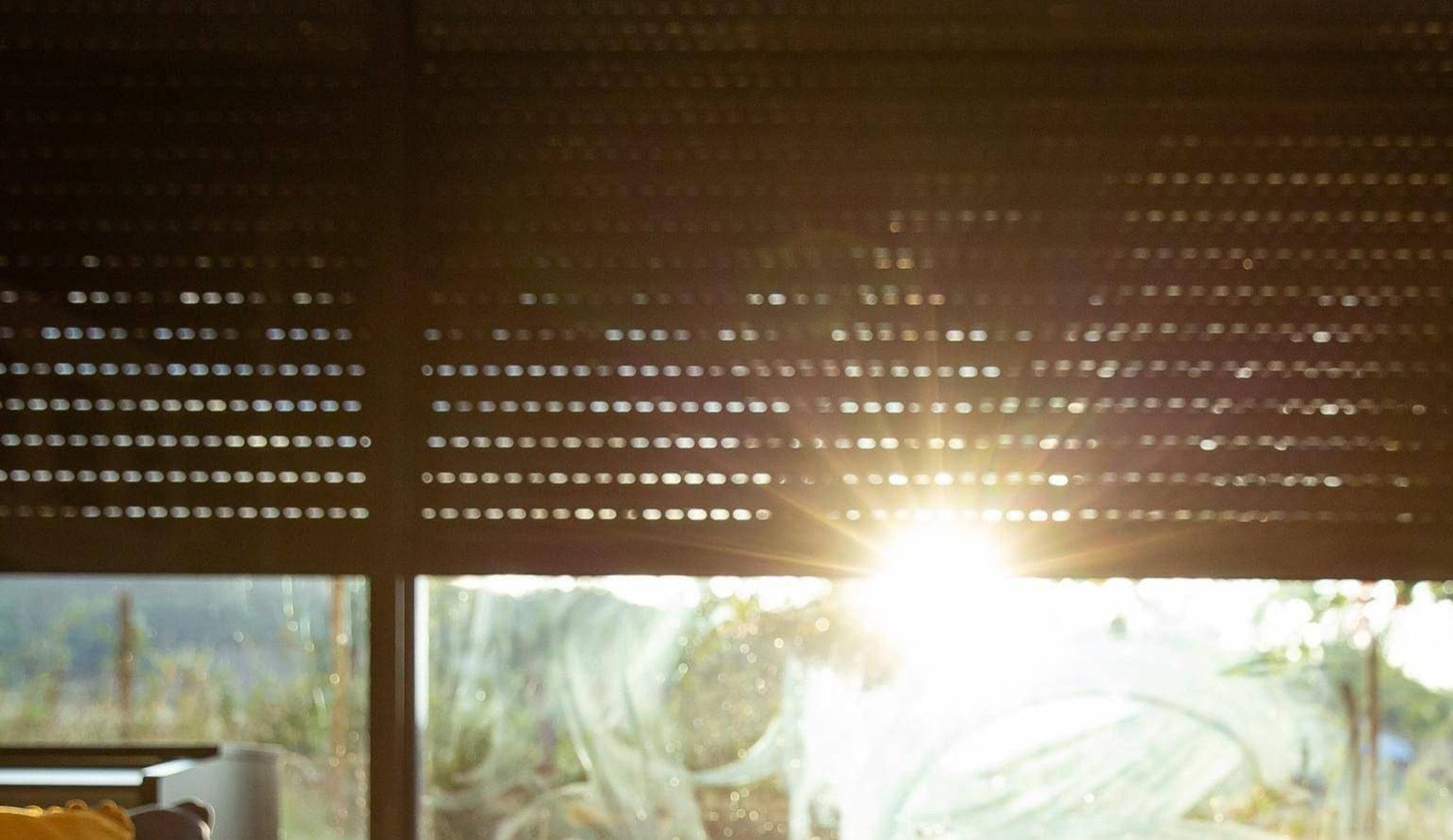 Pohled ven z okna s polozateženými solárními roletami