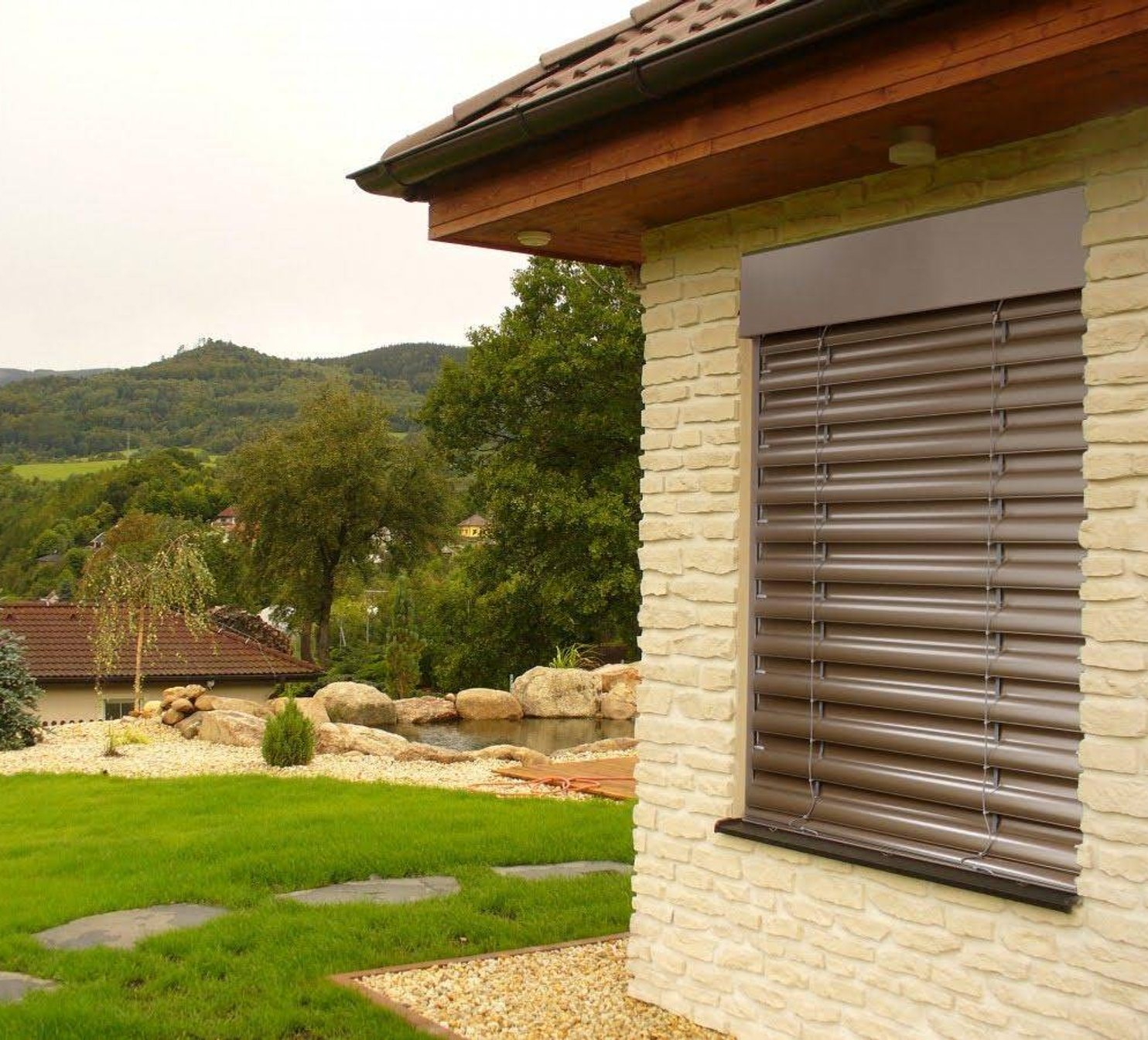 Venkovní žaluzie u kamenného domu