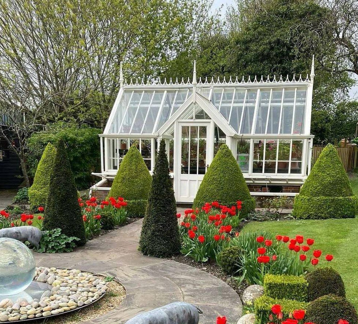 Viktorianský skleník na zahradě s květinami