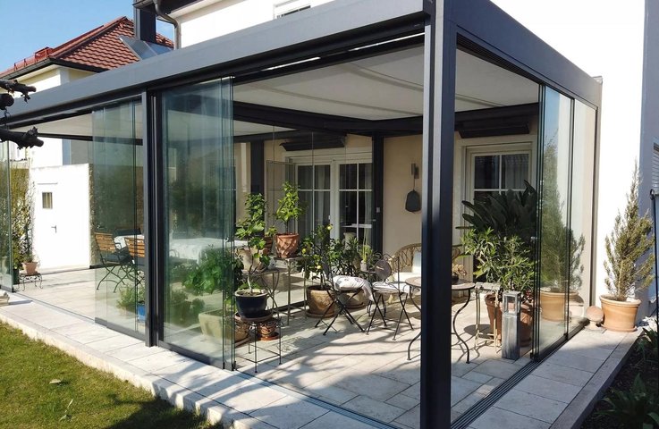 Plně zasklený hliníkový systém Hezký stín – prosklená pergola u rodinného domu proměněná v útulné posezení se zelení, chráněné před větrem a deštěm.