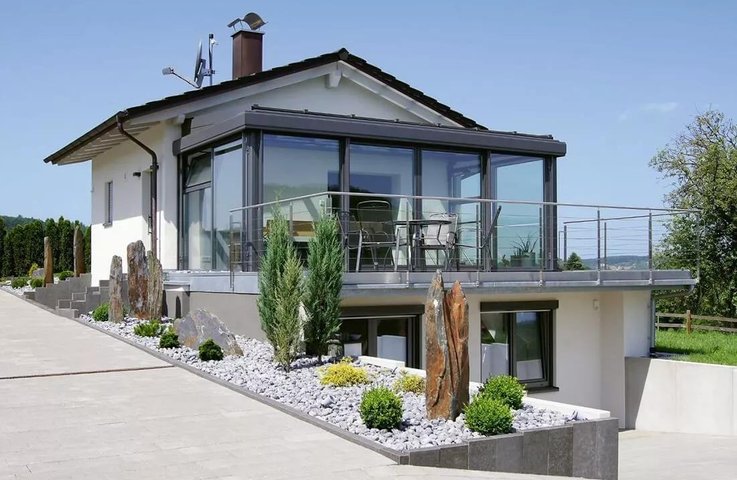 Celoroční zimní zahrada z hliníku a skla v patře rodinného domu s terasou, navazující na moderně řešenou zahradu – realizace Hezký stín.