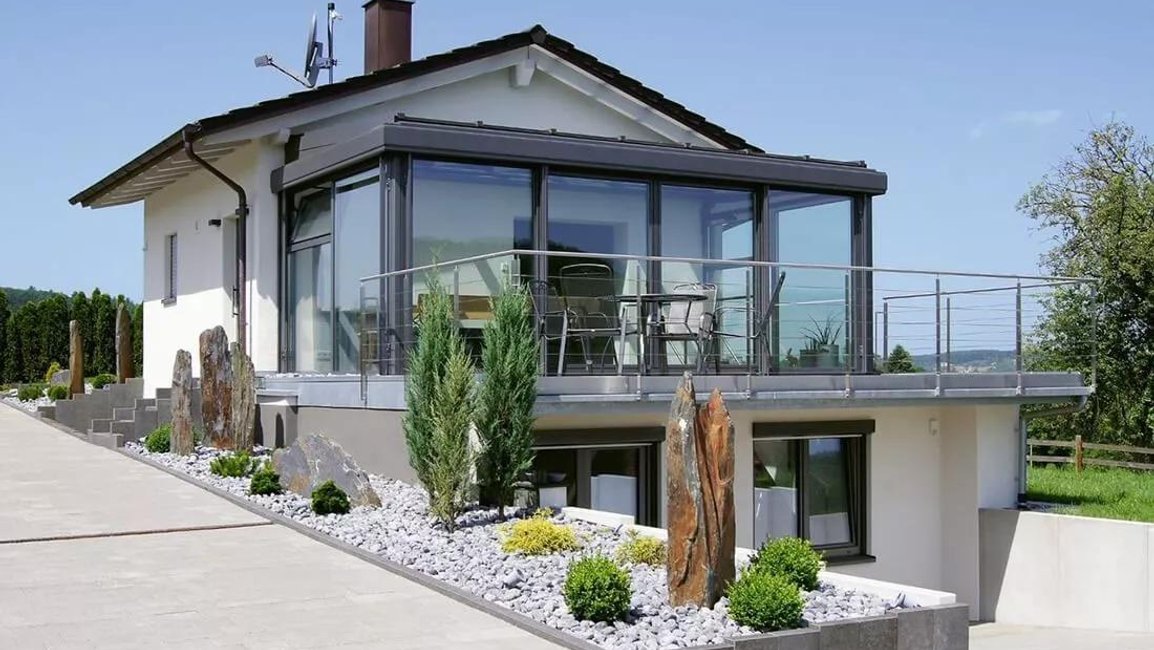 Celoroční zimní zahrada z hliníku a skla v patře rodinného domu s terasou, navazující na moderně řešenou zahradu – realizace Hezký stín.